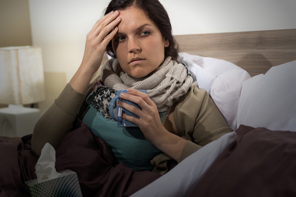 Young woman having flu sitting in bed