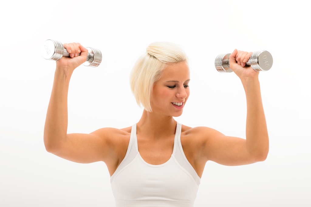 Fitness woman exercise biceps in studio lifting dumbbells
