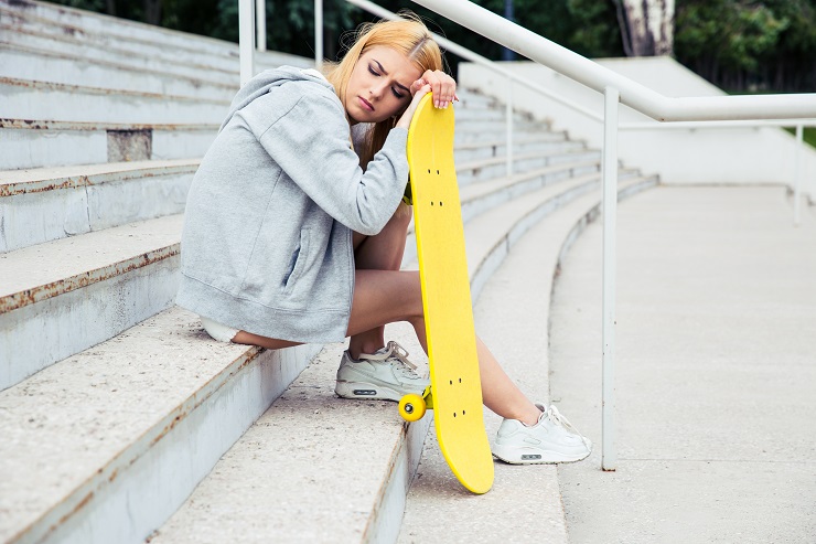 Young girl resting with skateboard on the park stairs