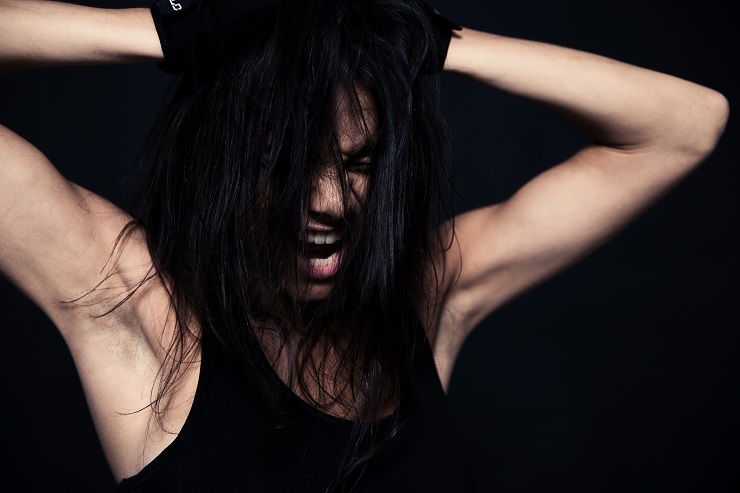 Portrait of a fitness woman screaming over black background