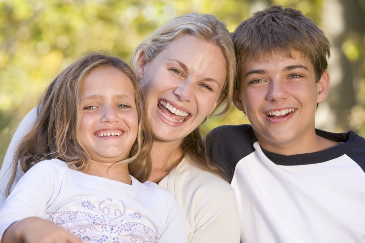 Woman and two young children outdoors laughing