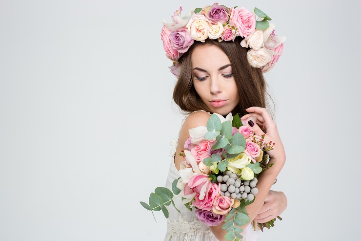 Romantic cute lovely young woman in beautiful wreath of roses posing with bouquet of flowers
