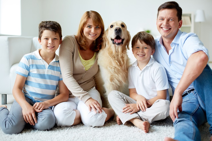 Portrait of happy family with fluffy Labrador having rest at home
