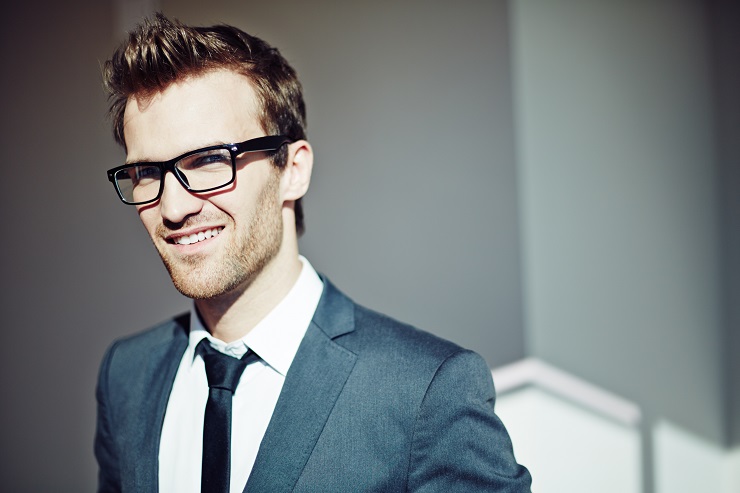 Confident young businessman in eyeglasses looking at camera