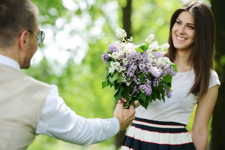 Portrait of a man hiding a flowers bouquet behind his back to surprise to a female